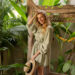 Beautiful blond woman in green dress posing outdoor during tropical vacations in Bali.