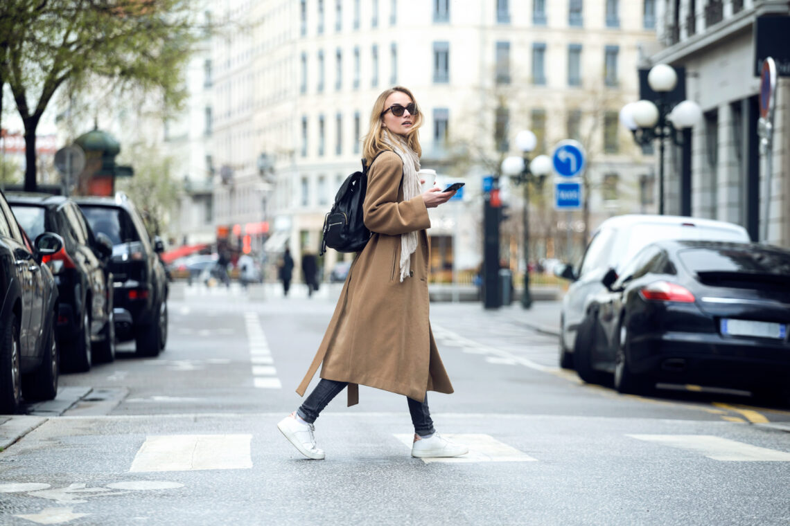 Woman holding coffee and walking down the street in the city